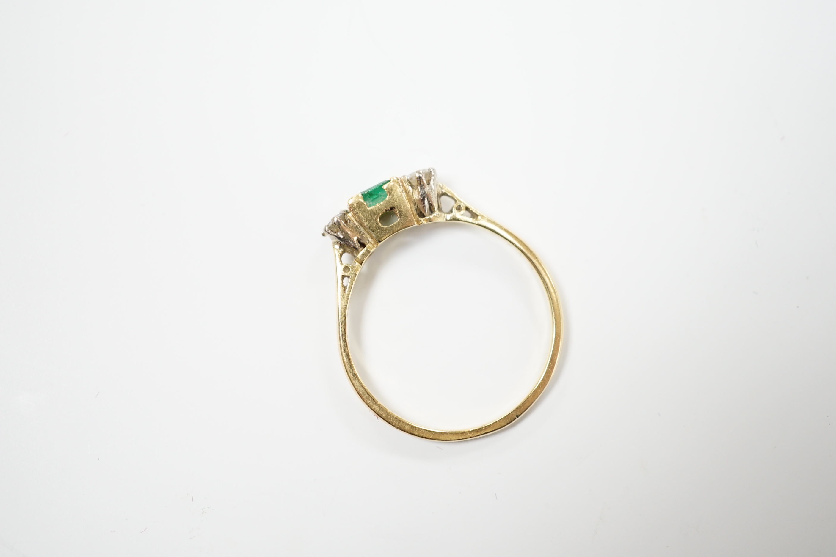 An 18ct and plat, single stone emerald and two stone diamond set ring, size Q/R, gross weight 2.6 grams.